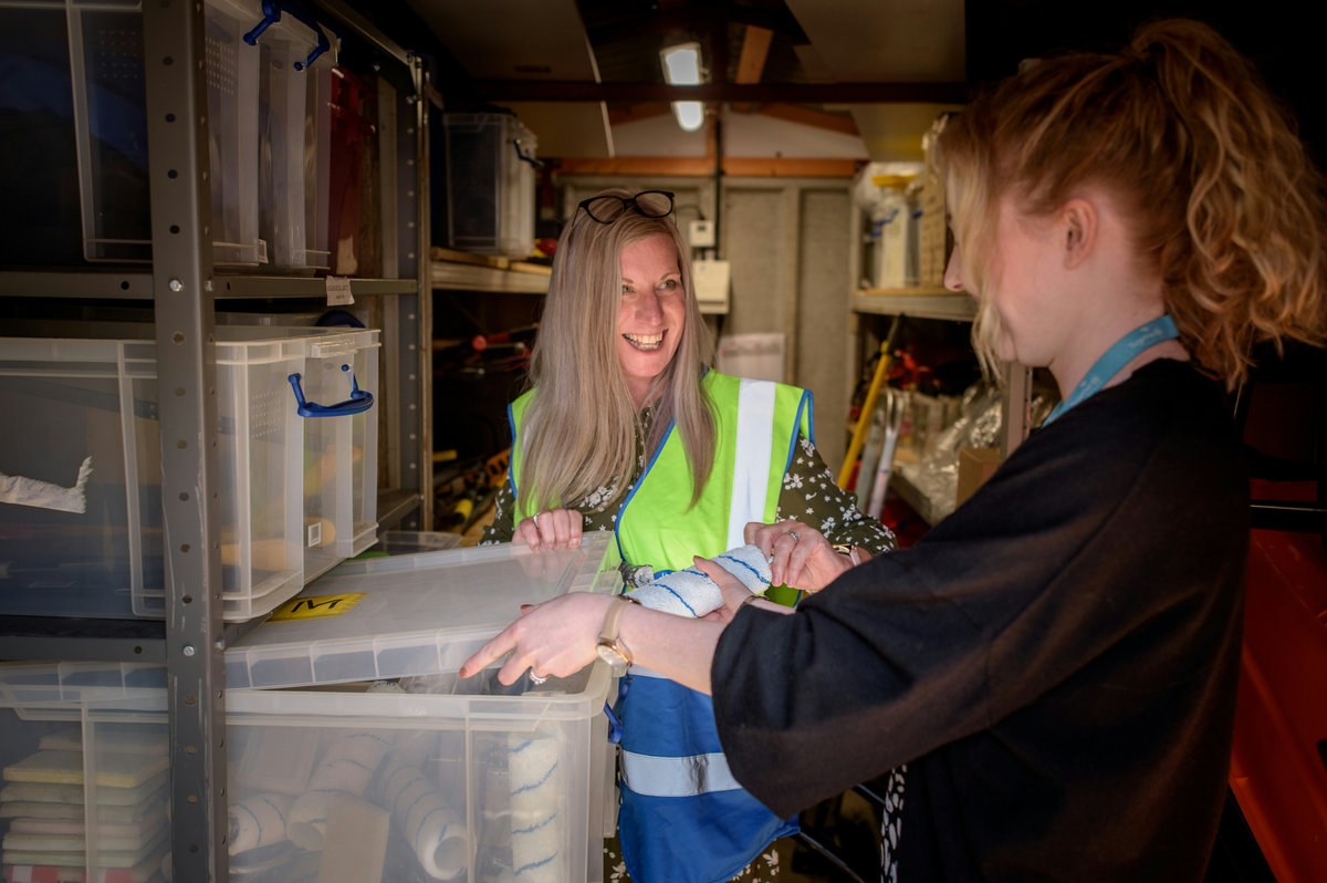 Two people working together among storage crates in a stockroom.